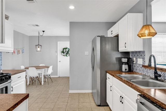 704 Firethorn Ln, Round Rock, TX 78664 - kitchen with a sink, stainless steel appliances, dark countertops, white cabinetry, and baseboards