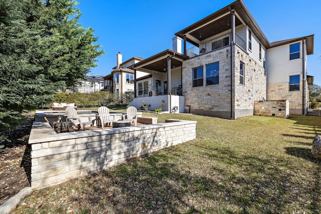 15089 Joseph Dr, Austin, TX 78734 - rear view of house featuring stone siding, a fire pit, a lawn, and a balcony