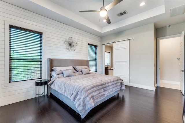 15089 Joseph Dr, Austin, TX 78734 - bedroom featuring a barn door, a tray ceiling, wood finished floors, wood walls, and recessed lighting