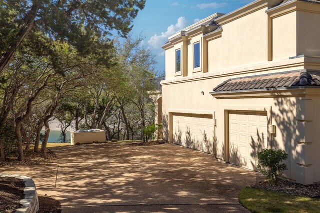 19801 Angel Bay Dr, Spicewood, TX 78669 - view of side of home featuring an attached garage, driveway, stucco siding, and a tiled roof