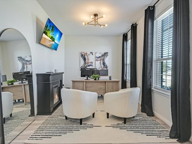218 Pearland St, Hutto, TX 78634 - dining room with a glass covered fireplace, a chandelier, light wood-type flooring, baseboards, and arched walkways