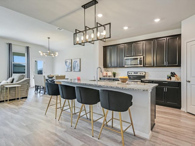 218 Pearland St, Hutto, TX 78634 - kitchen with a chandelier, appliances with stainless steel finishes, a sink, backsplash, and a breakfast bar area