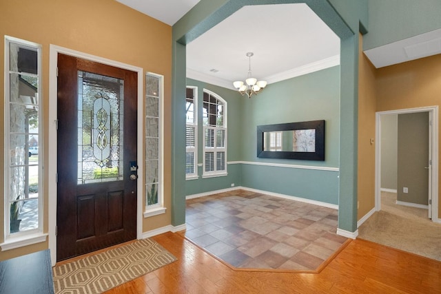 foyer entrance featuring a chandelier, wood finished floors, baseboards, and crown molding