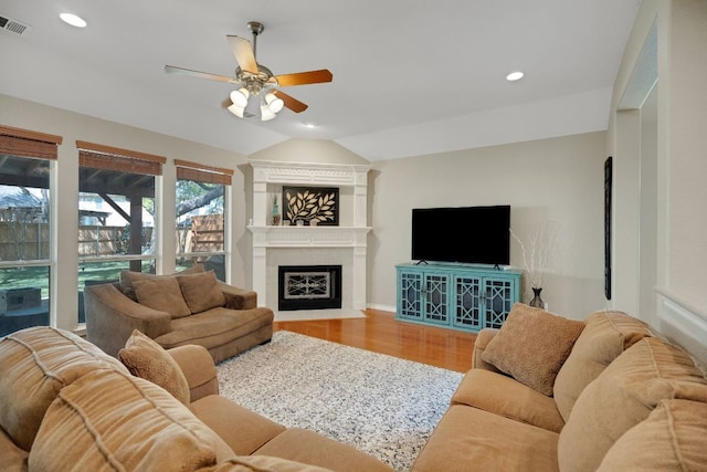 living area with ceiling fan, vaulted ceiling, wood finished floors, recessed lighting, and a fireplace with flush hearth