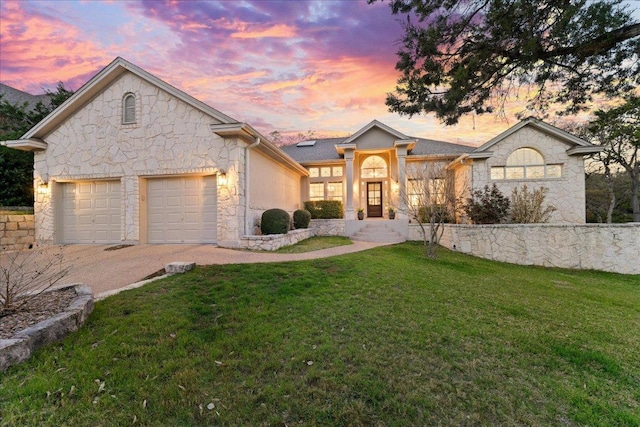 ranch-style home featuring stone siding, a front yard, driveway, and a garage