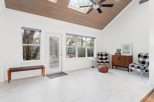 sitting room with high vaulted ceiling, a ceiling fan, a skylight, wood ceiling, and crown molding
