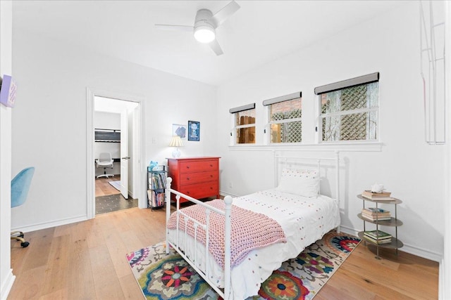 bedroom featuring light wood finished floors, baseboards, and a ceiling fan