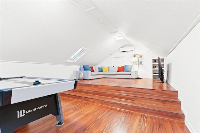 rec room featuring hardwood / wood-style floors, lofted ceiling, a wall mounted air conditioner, and baseboards