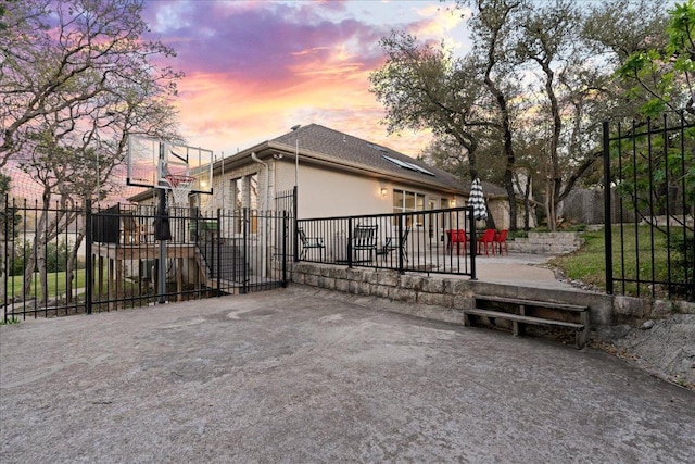 view of property exterior with fence, basketball court, and stucco siding