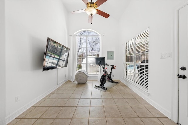 workout room featuring light tile patterned flooring, electric panel, baseboards, a towering ceiling, and a ceiling fan