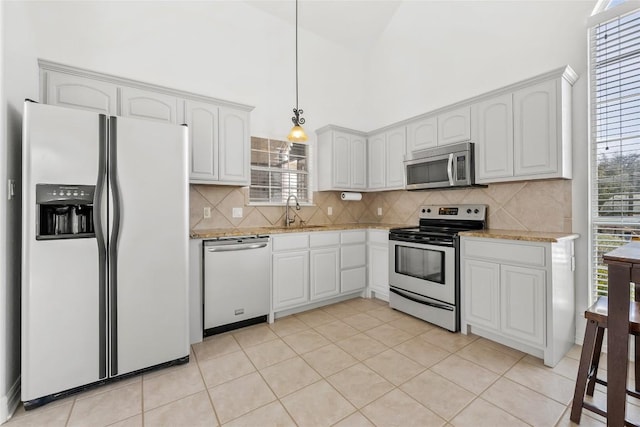 kitchen featuring high vaulted ceiling, a sink, backsplash, pendant lighting, and appliances with stainless steel finishes