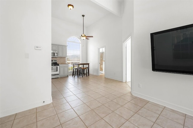 unfurnished living room with light tile patterned flooring, high vaulted ceiling, beam ceiling, a ceiling fan, and baseboards