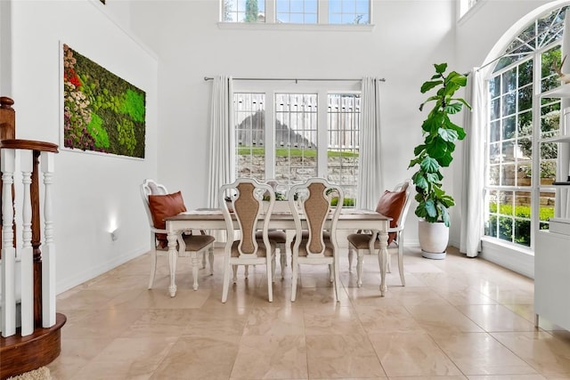 dining space with baseboards and a towering ceiling