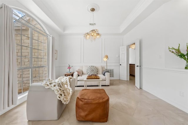 living area featuring a decorative wall, visible vents, crown molding, a tray ceiling, and a notable chandelier