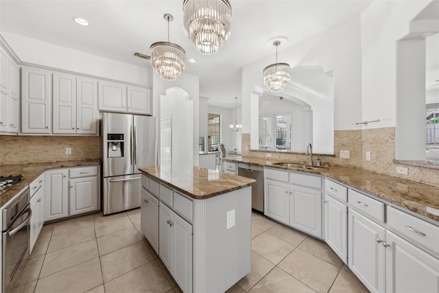 kitchen featuring a notable chandelier, a sink, a center island, light tile patterned floors, and stainless steel appliances