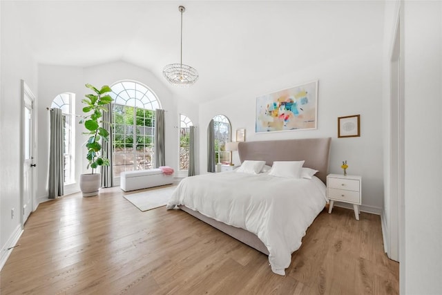 bedroom featuring baseboards, high vaulted ceiling, light wood-style flooring, and a chandelier