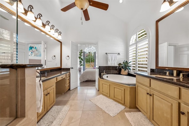 bathroom with ceiling fan, tile patterned floors, two vanities, a sink, and a garden tub