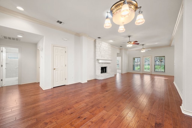 183 Augusta Dr, Wimberley, TX 78676 - unfurnished living room featuring crown molding, a ceiling fan, hardwood / wood-style floors, a stone fireplace, and a chandelier