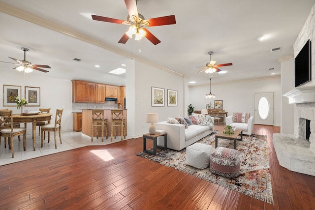 183 Augusta Dr, Wimberley, TX 78676 - living room with a fireplace with raised hearth, ceiling fan, light wood-style flooring, crown molding, and recessed lighting