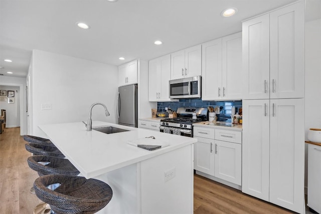 6306 Arnold Dr Unit 1, Austin, TX 78723 - kitchen featuring appliances with stainless steel finishes, a sink, light wood finished floors, white cabinets, and recessed lighting