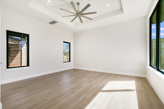 123 Azalea Loop, Horseshoe Bay, TX 78657 - empty room featuring a tray ceiling, light wood-style floors, a ceiling fan, and baseboards