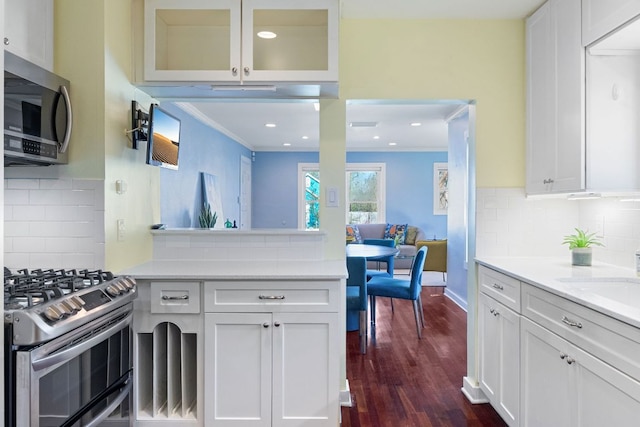 4419 Sinclair Ave, Austin, TX 78756 - kitchen with stainless steel appliances, dark wood-type flooring, white cabinets, ornamental molding, and light countertops