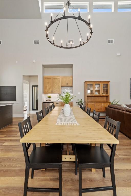200 County Road 246, Florence, TX 76527 - dining area with a high ceiling, a chandelier, light wood finished floors, and baseboards