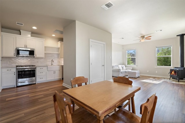 200 County Road 246, Florence, TX 76527 - dining room featuring a wood stove, dark wood-style flooring, ceiling fan, baseboards, and recessed lighting