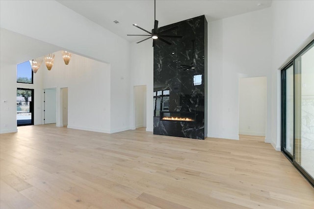 317 Azalea Ct, Horseshoe Bay, TX 78657 - unfurnished living room featuring a high ceiling, wood finished floors, a ceiling fan, a fireplace, and a chandelier