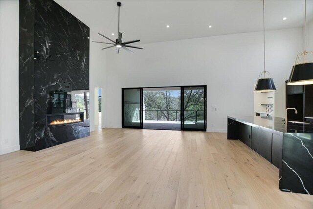 317 Azalea Ct, Horseshoe Bay, TX 78657 - living room with a towering ceiling, light wood-type flooring, a ceiling fan, baseboards, and a high end fireplace
