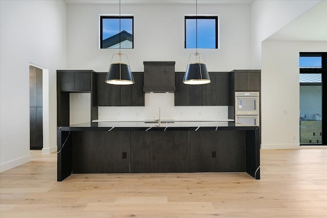 317 Azalea Ct, Horseshoe Bay, TX 78657 - kitchen featuring a sink, a large island, white double oven, a towering ceiling, and decorative light fixtures
