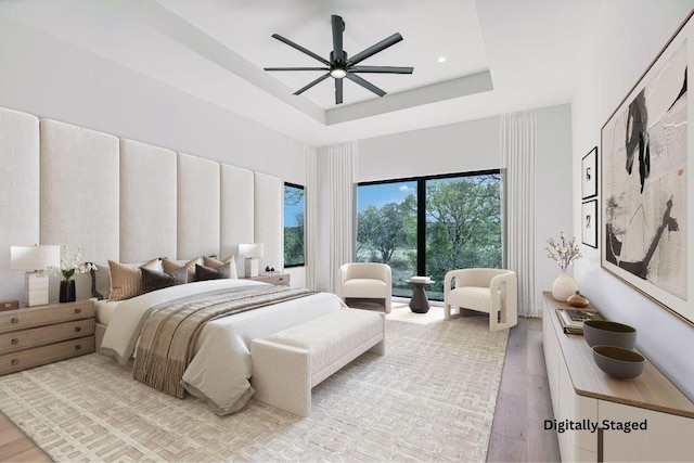317 Azalea Ct, Horseshoe Bay, TX 78657 - bedroom with wood finished floors, a tray ceiling, ceiling fan, and a towering ceiling