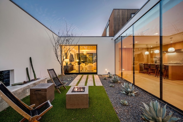 exterior space featuring a patio, a fire pit, a yard, and stucco siding