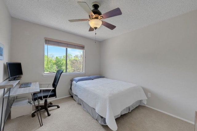 bedroom with light carpet, baseboards, ceiling fan, and a textured ceiling