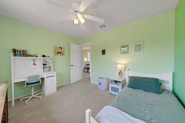 carpeted bedroom featuring a ceiling fan, visible vents, baseboards, and a textured ceiling