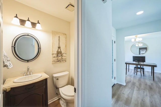 bathroom featuring visible vents, baseboards, toilet, wood finished floors, and vanity