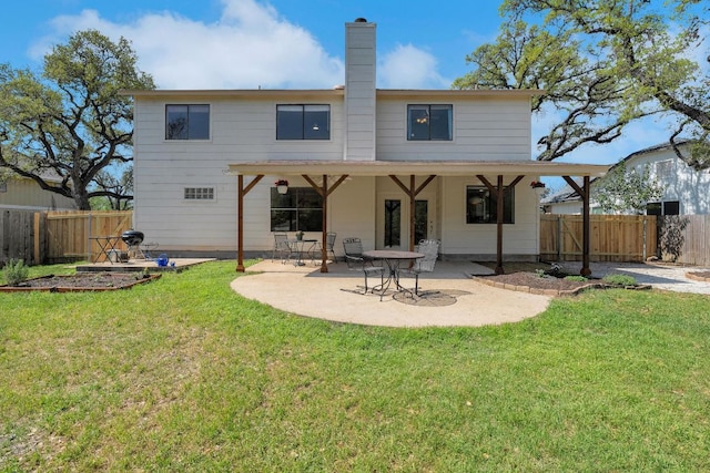 rear view of property with a lawn, a chimney, a fenced backyard, and a patio area