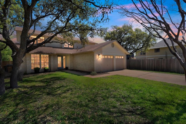 view of front of property featuring driveway, fence, brick siding, a garage, and a yard