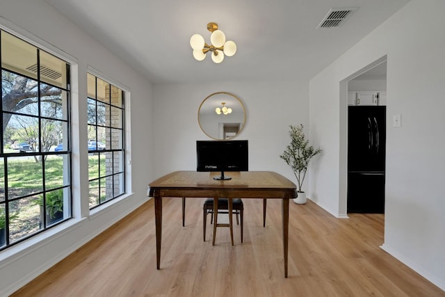 office featuring light wood-style flooring, visible vents, a notable chandelier, and plenty of natural light
