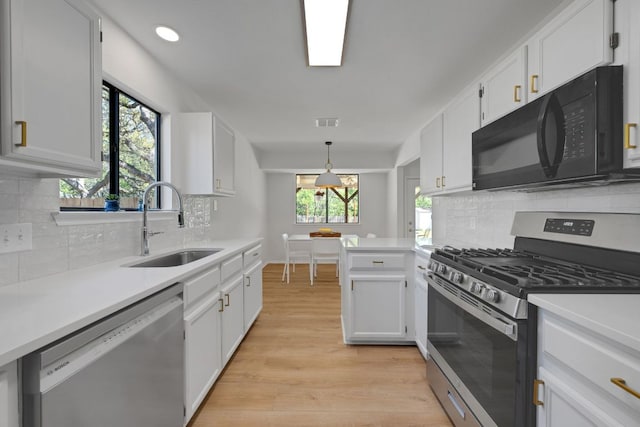 kitchen with light countertops, a sink, appliances with stainless steel finishes, visible vents, and white cabinets