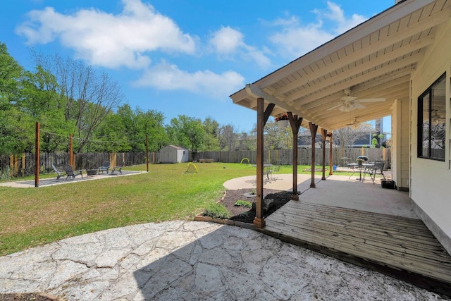 view of patio with an outbuilding, ceiling fan, a fenced backyard, and a storage unit