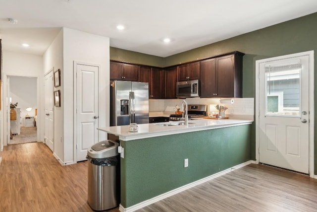 14128 Sandrock Bnd, Pflugerville, TX 78660 - kitchen featuring appliances with stainless steel finishes, a sink, light wood-type flooring, dark brown cabinetry, and light countertops