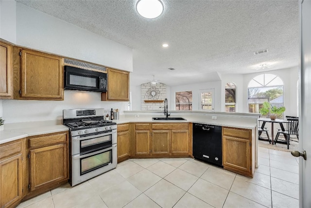 kitchen featuring light countertops, a sink, a peninsula, brown cabinets, and black appliances