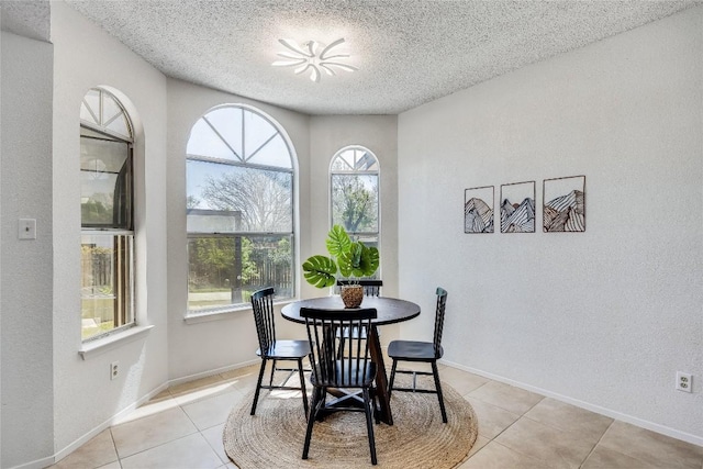 dining room featuring light tile patterned floors, plenty of natural light, baseboards, and a textured ceiling