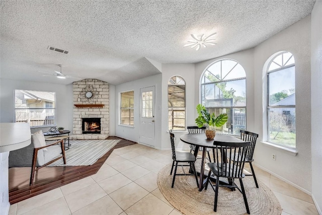 dining space featuring visible vents, a ceiling fan, a fireplace, and light tile patterned floors