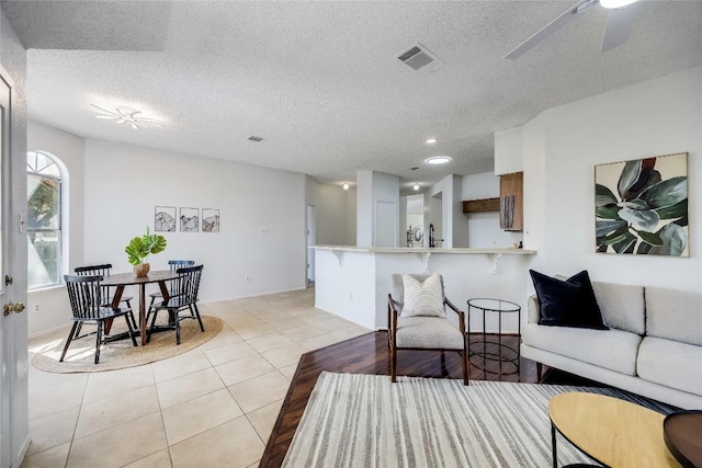 living area featuring a textured ceiling, light tile patterned floors, visible vents, ceiling fan, and recessed lighting