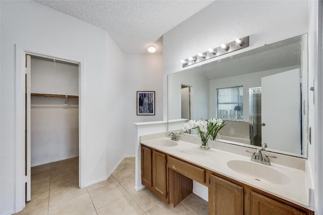 full bath with a textured ceiling, a sink, a stall shower, and tile patterned flooring