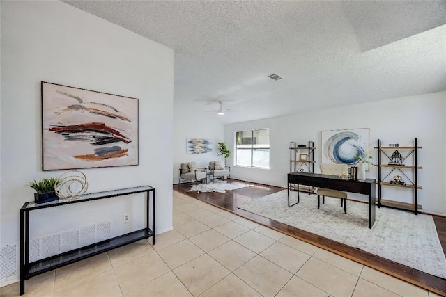 hall featuring light tile patterned floors, a textured ceiling, and visible vents