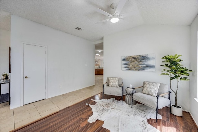 sitting room featuring wood finished floors, a textured ceiling, lofted ceiling, visible vents, and ceiling fan