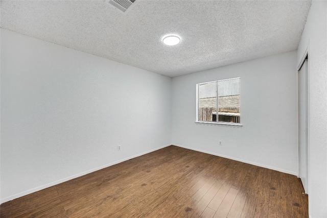 empty room with baseboards, a textured ceiling, visible vents, and wood finished floors